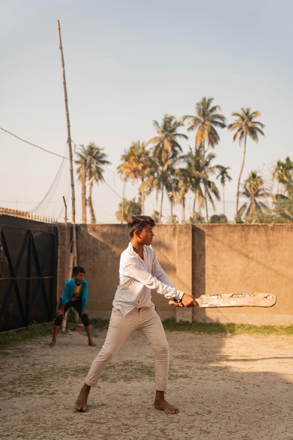 Boy batting cricket at sunset
